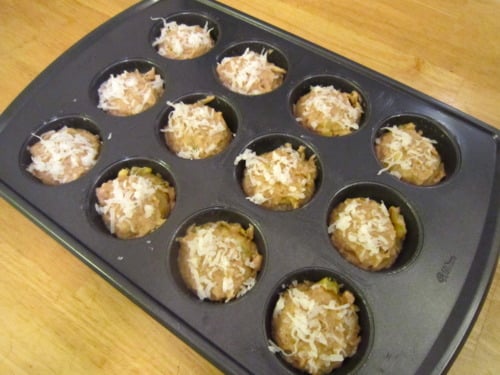 Muffin tin filled with banana coconut pineapple muffin batter, topped with shredded coconut and ready for baking.