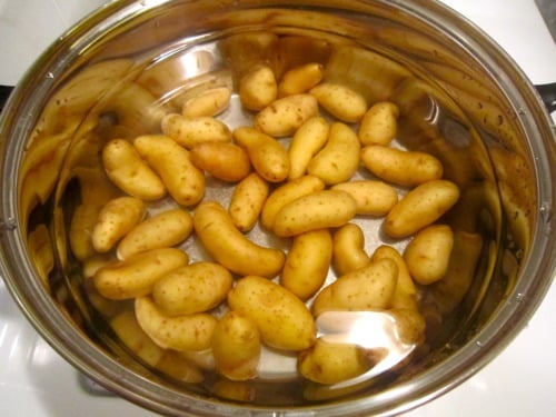 Fingerling potatoes soaking in a pot of water before cooking.