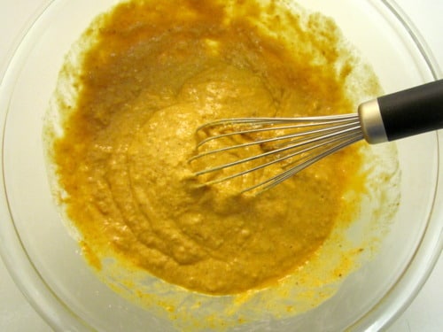 Pumpkin pancake batter being mixed in a glass bowl with a whisk.