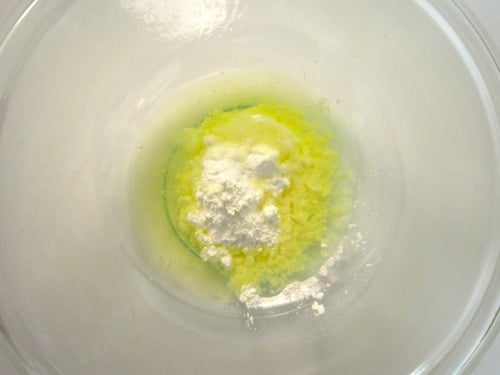 Cornstarch, egg white, and seasoning mixture in a glass bowl, prepared as a coating for lighter sesame chicken.