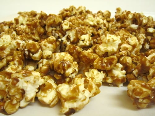 Close-up of caramel-coated popcorn spread out on a white surface.