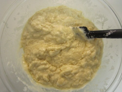 Peach champagne cupcake batter mixed in a glass bowl with a black spatula, ready for baking.