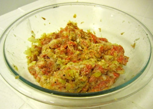Raw meatball mixture in a clear glass bowl, showing ground meat combined with breadcrumbs, grated vegetables, and seasonings before shaping and cooking.