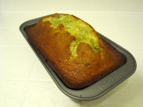 Freshly baked Meyer lemon and matcha marble pound cake in a loaf pan, with a golden brown crust and green matcha swirls.