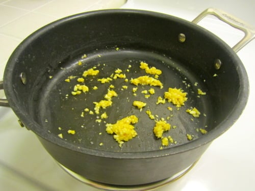 Minced garlic and ginger sautéing in a black saucepan for Thai coconut curry sauce.