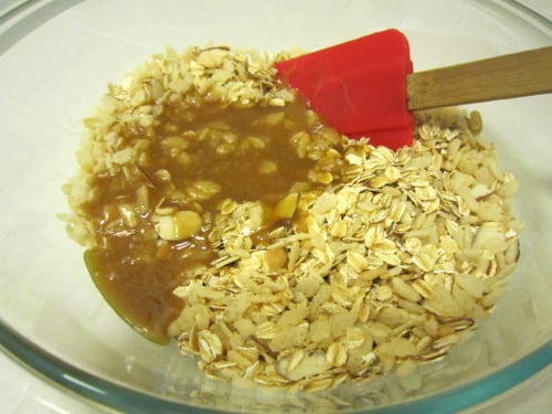 Oats and almond mixture being combined with honey mixture for no-bake granola bars.