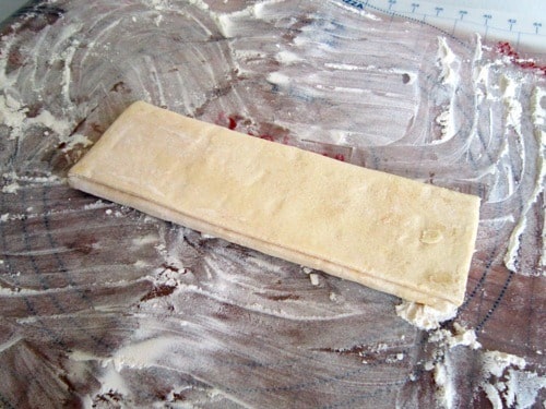 Frozen puff pastry sheet on a floured surface, prepared for making an asparagus and Gruyère tart.