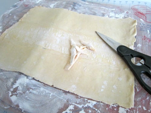 Puff pastry sheet dusted with flour and trimmed with kitchen scissors.