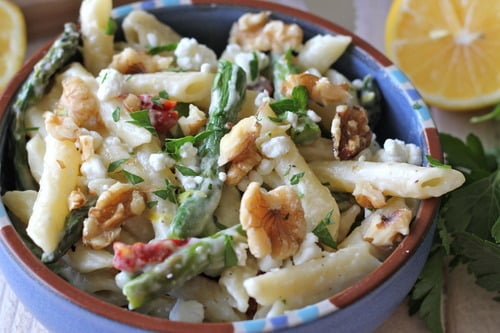 Bowl of creamy Meyer lemon pasta with asparagus, walnuts, and herbs.