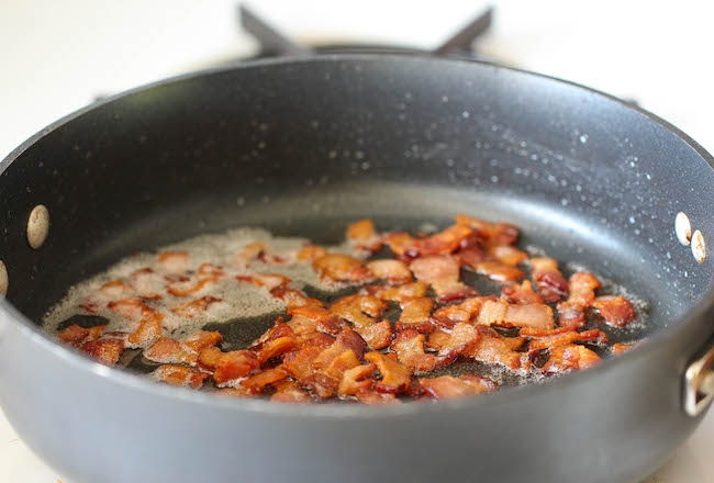 A crispy pancetta and a sprinkle of black pepper getting cook as toppings for spaghetti carbonara
