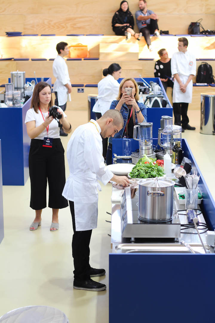 Chef preparing ingredients at a cooking station during the Pasta World Championship 2017, surrounded by media and onlookers.