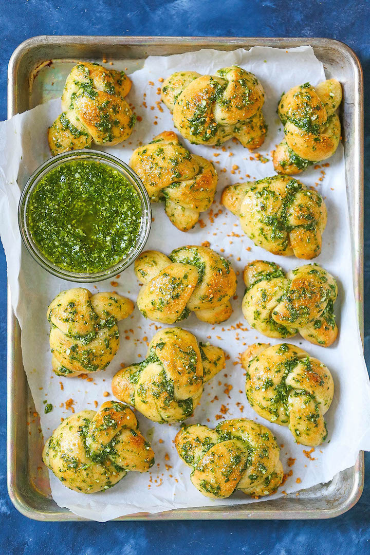 Pesto Garlic Knots - So garlicky, so buttery, and just so perfect! They are incredibly soft and melt-in-your-mouth amazing with a homemade pesto sauce. These also come together in less than 15 minutes using pizza dough. See, it really is SO EASY!