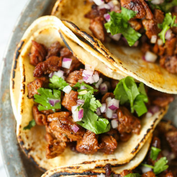 Street tacos served with onion, cilantro, and lime on corn tortillas