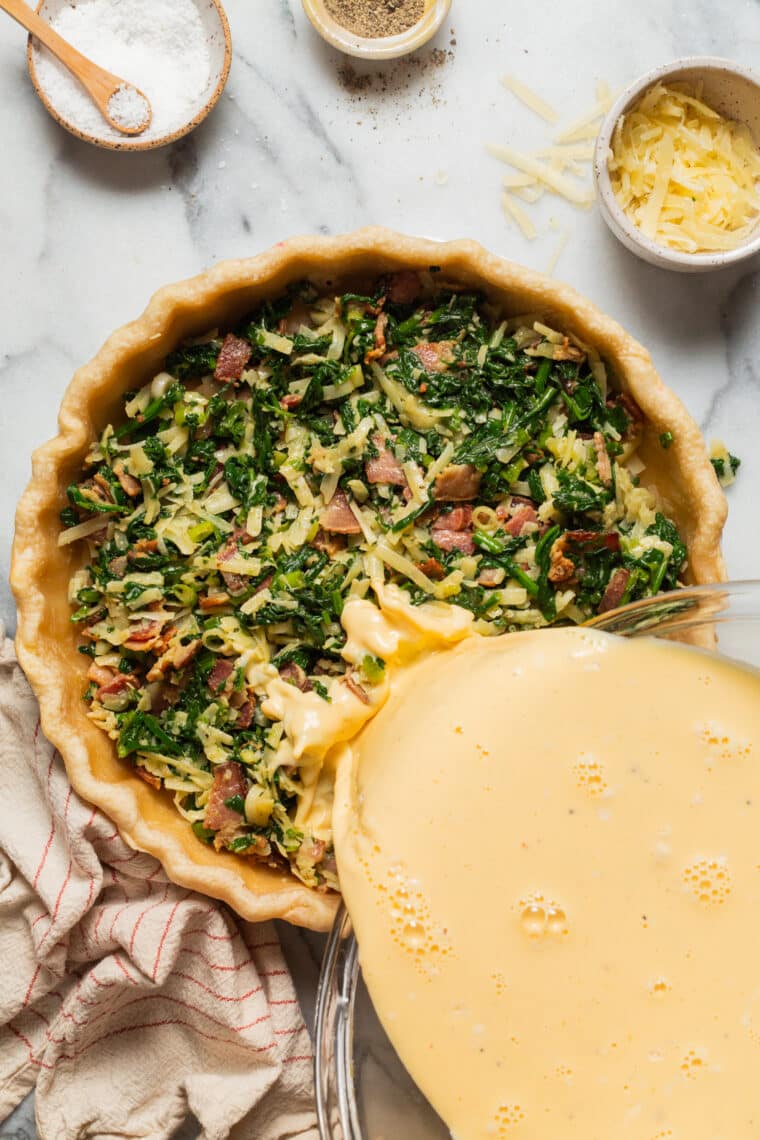 pouring egg mixture into pie crust for easy quiche
